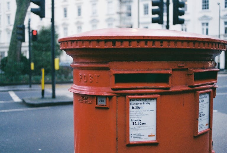 A traditional red post box on a London street corner, capturing the essence of city life.